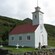 A small wooden chapel surrounded by greenery